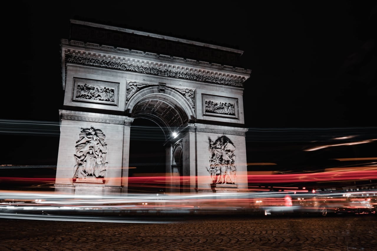 Stunning night shot of the Arc de Triomphe in Paris with dynamic light trails from passing cars.